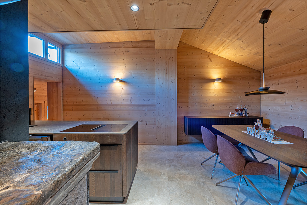 Modernisierter Wohn- und Essbereich nach dem Wohnungsumbau in Bellwald mit hellen Holzverkleidungen, sichtbarer Dachschräge und neu gestalteter Raumstruktur.