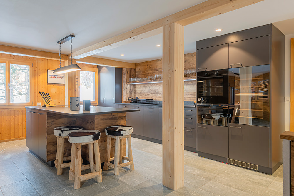 Küchenumbau im Oberwallis aus einer Hand – moderne Küche mit Kochinsel, Altholz und massgefertigten Möbeln.