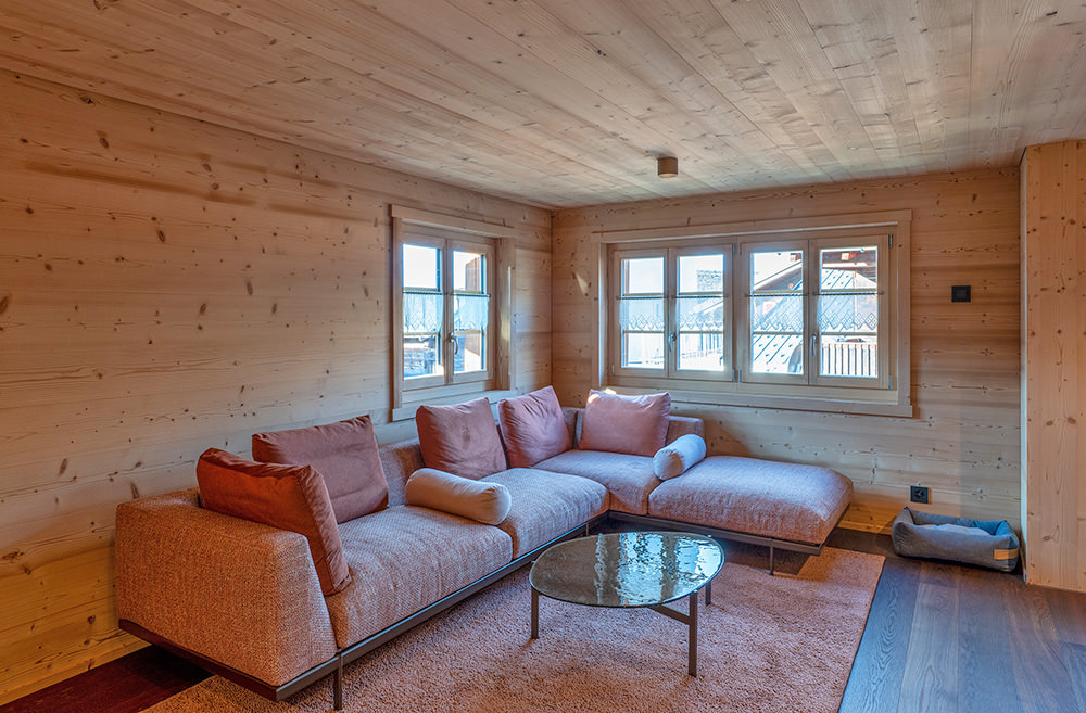 Wohnbereich nach dem Wohnungsumbau im Oberwallis mit Holzverkleidung, grossen Fenstern und hellem Innenausbau