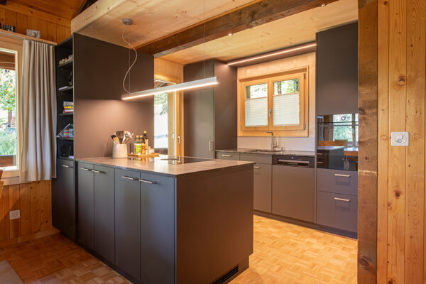 Moderne Küche mit Kochinsel und LED-Beleuchtung nach Komplettumbau durch Schreinerei Perren im Oberwallis